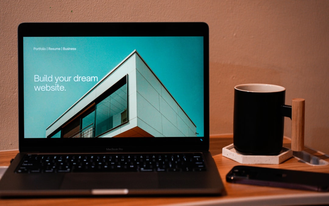 Create the website you’ve always imagined for your future. A laptop, MacBook, placed on a portable table, with a coffee or tea mug beside it.
